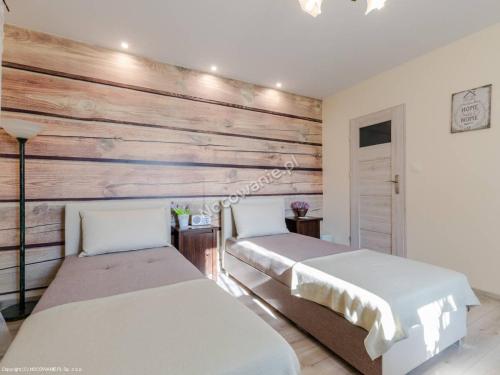 two beds in a room with a wooden wall at Agroturystyka DANA in Debrzno
