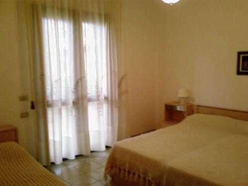 sypialnia z 2 łóżkami i oknem z zasłonami w obiekcie Villa Flamicia 1P w Lignano Sabbiadoro