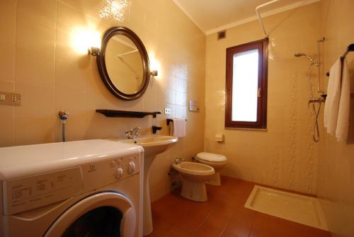 łazienka z pralką, umywalką i toaletą w obiekcie Villa Flamicia 1P w Lignano Sabbiadoro