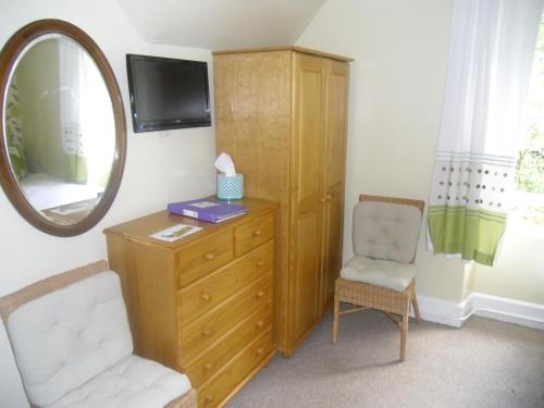a room with a dresser and a mirror and a chair at Ormidale Hotel in Brodick