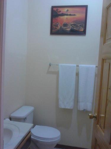 a bathroom with a toilet and a sink and towels at Sea Shell Palms, Ocho Rios in Ocho Rios