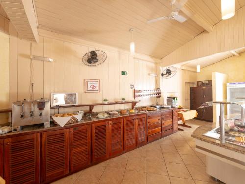a large kitchen with wooden cabinets and a counter at Hotel Saveiros in Ubatuba