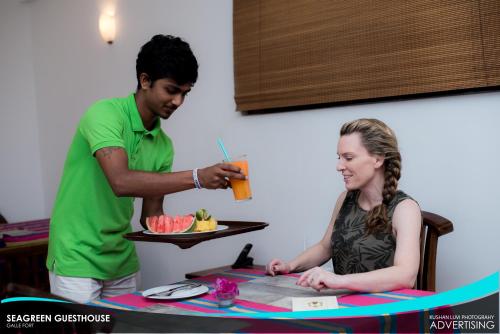a man and a woman sitting at a table with a plate of food at Seagreen Guesthouse - Galle Fort in Galle
