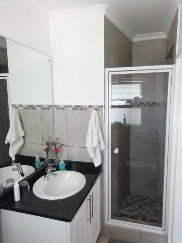 a bathroom with a white sink and a shower at Maroela House Guest Accommodation in Bellville