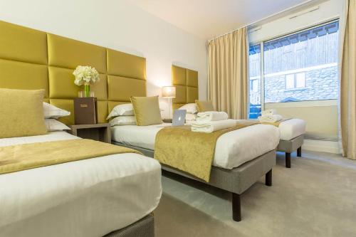a hotel room with two beds and a window at Madame Vacances - Hôtel Courchevel Olympic in Courchevel