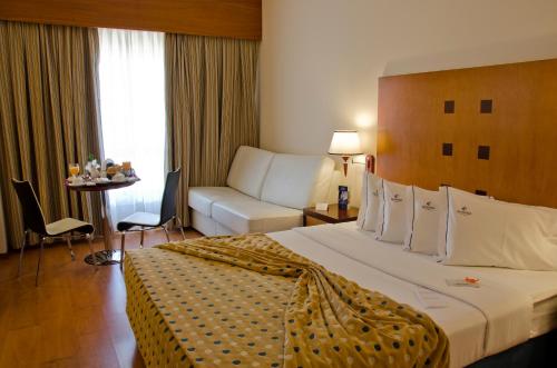 a hotel room with a large bed and a couch at VIP Executive Santa Iria Hotel in Santa Iria da Azóia