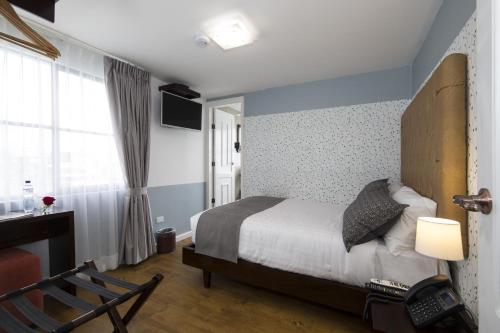 a bedroom with a bed and a chair and a window at TERRA PREMIUM Hostal Boutique in Quito