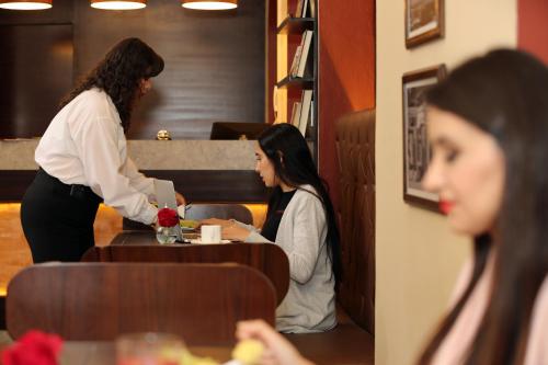 two women in a kitchen looking at a menu at TERRA PREMIUM Hostal Boutique in Quito