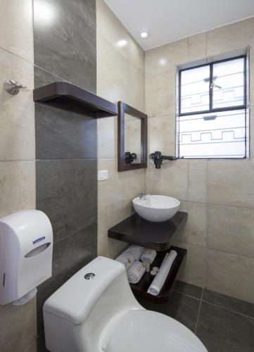 a bathroom with a white toilet and a sink at TERRA PREMIUM Hostal Boutique in Quito