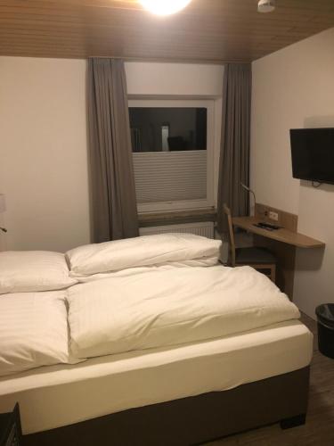 a bedroom with a bed and a desk and a window at Heeren's Hotel Garni in Bensersiel