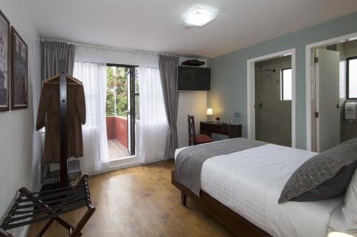 a bedroom with a bed and a chair and a window at TERRA PREMIUM Hostal Boutique in Quito