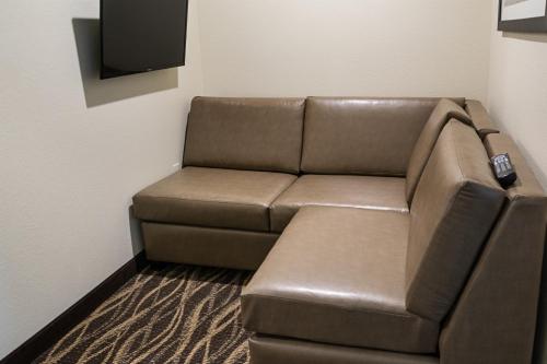 a brown leather couch in a room with a tv at Cobblestone Inn and Suites - Ashland in Ashland