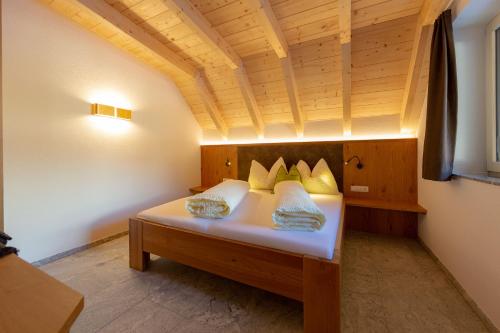 a bed in a room with a wooden ceiling at Alpen Apart Heiss - DELUXE XL Apartments in Prutz