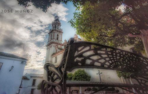 a bench in front of a building with a clock tower at Casa Cueva El Pocito in Peñaflor