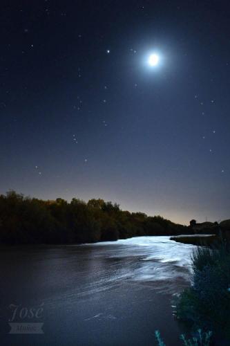 a moon and stars over a river at night at Casa Cueva El Pocito in Peñaflor