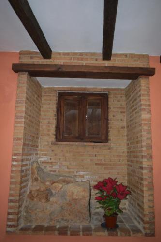 a brick fireplace with a window and a potted plant at Casa Cueva El Pocito in Peñaflor