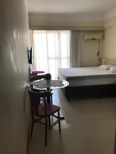a small room with a bed and a table and chairs at Apartamento Studio in Balneário Camboriú
