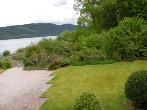 a grassy yard with a pathway next to a body of water at Thistle House Guest House in Saint Catherines