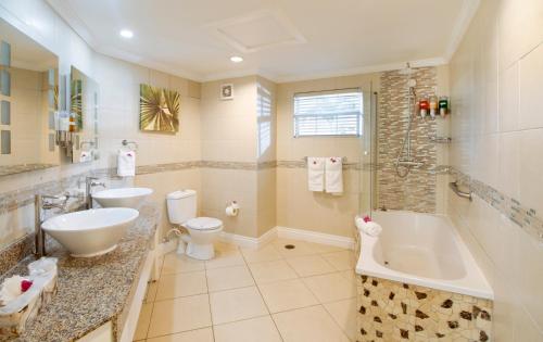 a bathroom with a tub and a toilet and a sink at Bay Gardens Beach Resort & Spa in Gros Islet