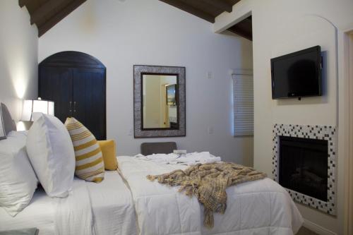 a bedroom with a large white bed with a fireplace at Andreas Hotel & Spa in Palm Springs