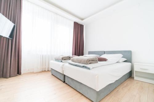 een witte slaapkamer met een bed en een raam bij Apartman Skenderija in Sarajevo