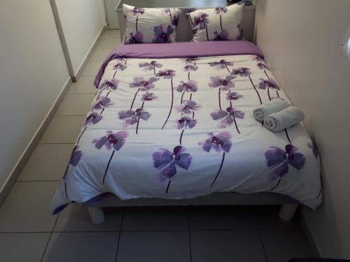 a bed with purple flowers on it in a room at studio climatisé in Avignon