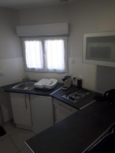 a kitchen with a stove and a sink and a window at studio climatisé in Avignon