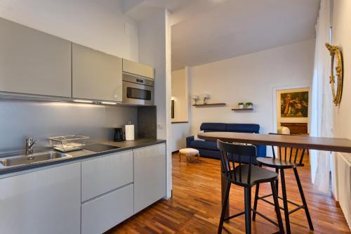 a kitchen with white cabinets and a bar with two chairs at Appartamenti Tommasini in Bologna