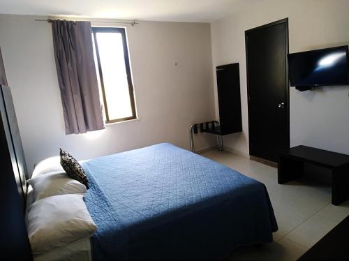 a bedroom with a blue bed and a television at Hotel HAUS Express in Orizaba