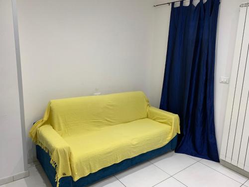a yellow bed in a room with a blue curtain at Appartamento Regonini in Alassio