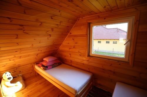 Cama pequeña en una cabaña de madera con ventana en Domek letniskowy Orzechowa en Giżycko