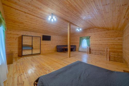 a large wooden room with a bed and a mirror at Райский Дворик in Pogreby