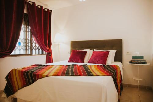 a bedroom with a bed with a colorful blanket and a window at Home Nina in Playa de las Americas