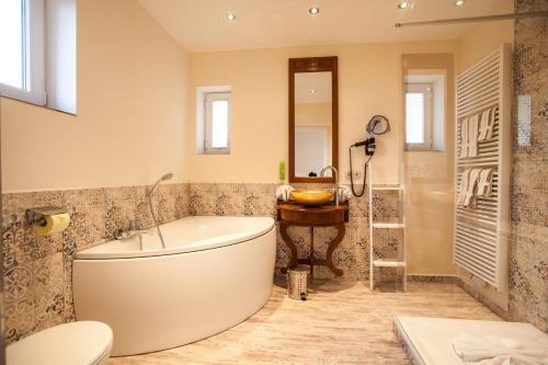ein Badezimmer mit einer großen Badewanne und einem Waschbecken in der Unterkunft HOTEL DÜNENLÄUFER Langeoog in Langeoog