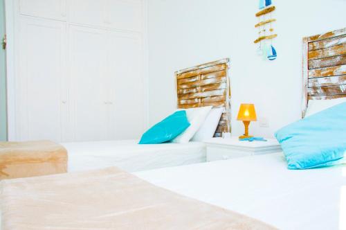 a white bedroom with two beds and a lamp at Casa Ada 2 in Famara
