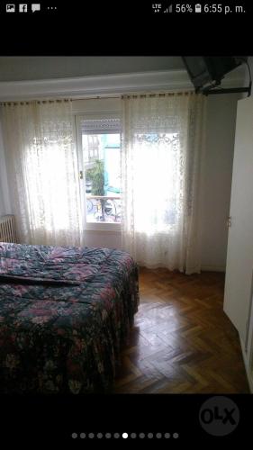 1 dormitorio con 1 cama y una ventana con cortinas en Semi piso 140 m2 Mar del Plata en Mar del Plata