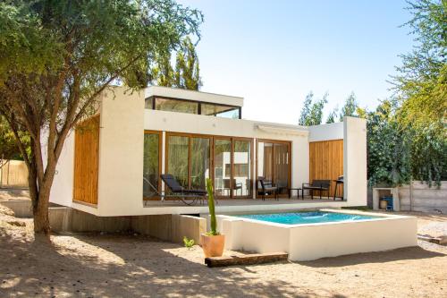 a modern house with a swimming pool and a tree at Aldea del Valle - Elqui Villas, Pisco Elqui in Pisco Elqui