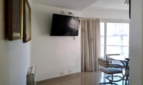 Habitación con mesa y TV en la pared. en Mar del Plata en Mar del Plata