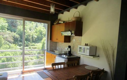 een keuken met een tafel, een magnetron en een raam bij Ayios Andronikos Agrotourism House in Kalopanayiotis