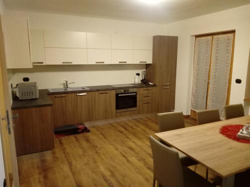 a kitchen with a table and a dining room at Appartamento Cristallo di Ghiaccio in Passo del Tonale