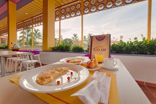 uma mesa com um prato de comida e uma chávena de sumo de laranja em Hotel Mocawa Resort em La Tebaida