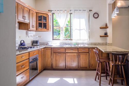 a kitchen with wooden cabinets and a sink and a window at Zula Inn Aparthotel in Santa Teresa Beach