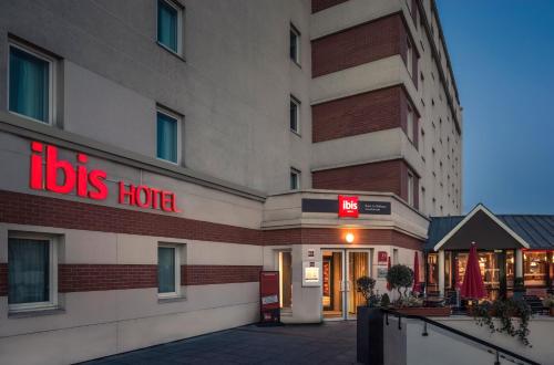 a hotel with a red sign on the side of it at ibis Paris La Defense Courbevoie in Courbevoie