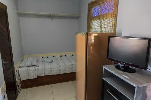 a small room with a bed and a tv at Pousada Fortaleza in Canoa Quebrada