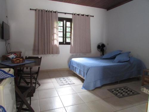 a bedroom with a bed and a desk and a window at Pousada Som das Águas Bueno Brandão in Bueno Brandão