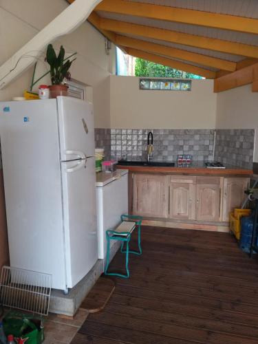 a kitchen with a white refrigerator and wooden cabinets at Le Nid De Nicolas in Saint Esprit