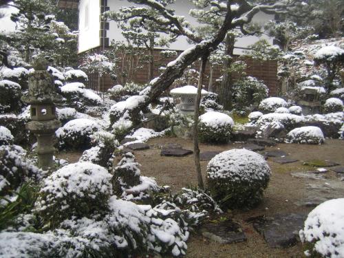 a garden covered in snow in front of a house at Japanese Style Inn Dohzen Miwa in Niimi