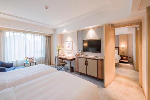 a hotel room with a bed and a desk with a television at Shangri-La Changchun in Changchun