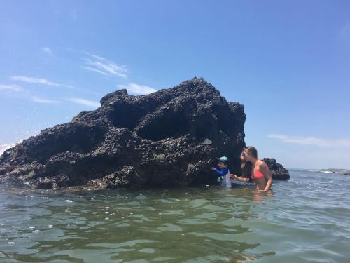a woman and a child in the water near a rock at El Samay Hotel Boutique in Canoas De Punta Sal