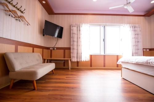 仁愛鄉的住宿－清境繽紛農場，一间卧室配有一张床、一把椅子和电视